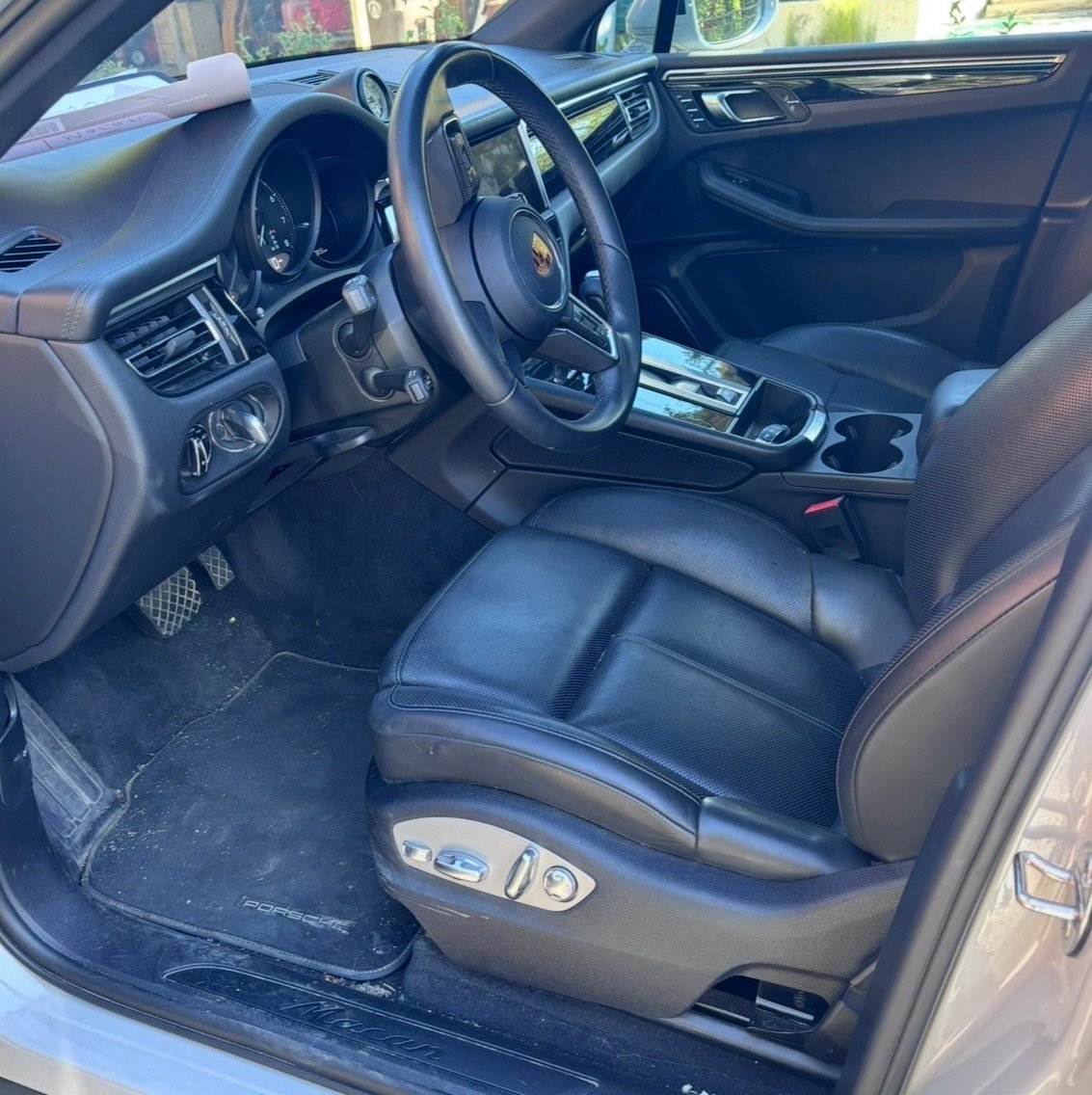 Interior view of a luxury sports car with black leather seats, steering wheel, and dashboard visible through open drivers door