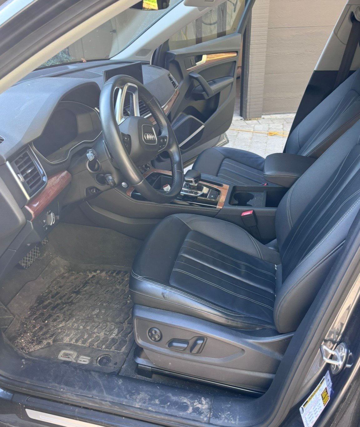 Interior view of a car showing steering wheel, dashboard, and black leather seats with chrome trim details
